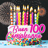 Centesimo compleanno in GIF animata: torta bianca monumentale, scritte rosa grandi e un cielo interamente illuminato da fuochi d'artificio.