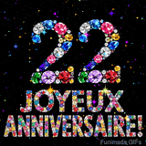 Le chiffre 22 et le lettrage Joyeux Anniversaire réalisés en joyaux éclatants de diverses couleurs sur une toile noire avec des étincelles.