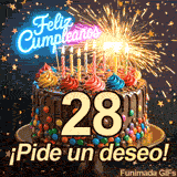 Torta adornada con dulces y el número 28. Una bengala encendida emite destellos festivos mientras cae confeti dorado alrededor de ¡Pide un deseo!.