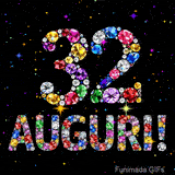 Immagine animata che mostra il numero 32 e Auguri in cristalli multicolori brillanti, circondati da piccole luci su uno sfondo scuro.