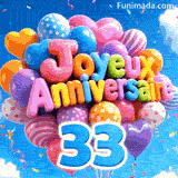 Flottant doucement devant des nuages blancs, cette grappe de ballons colorés présente le texte Joyeux Anniversaire et le chiffre bleu 33.
