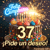 Torta de celebración con el número 37 en el centro. El letrero luminoso de Feliz Cumpleaños brilla entre destellos y estrellitas doradas.