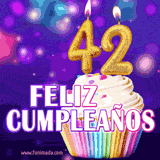 GIF animado de un cupcake decorado con confites, dos velas doradas encendidas formando el número 42, sobre un fondo púrpura brillante con destellos.