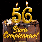 GIF animato con una torta al cioccolato decorata con crema, dettagli dorati e due candele accese che formano il numero 56. Messaggio 'Buon Compleanno' in scritta elegante.