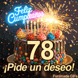 Torta decorada con dulces y el gran número 78. Una bengala encendida lanza luces brillantes bajo una lluvia de estrellas doradas y ¡Pide un deseo!.