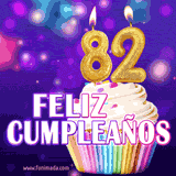 GIF animado de un cupcake decorado con confites, dos velas doradas encendidas formando el número 82, sobre un fondo púrpura brillante con destellos.