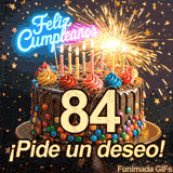 Destellos intensos iluminan un pastel que tiene el dígito 84. Lluvia dorada en forma de estrellas y letrero de Feliz Cumpleaños en la cima.