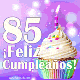 Animación de un cupcake con cobertura blanca, confites de colores, una vela encendida y el número 85 en grande sobre un fondo púrpura con luces brillantes.