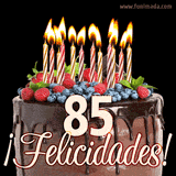 Animación de un pastel de chocolate decorado con frutas, velas encendidas y el número 85, acompañado de la palabra '¡Felicidades!' en elegante tipografía.