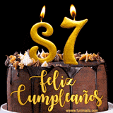 GIF de un pastel de chocolate con decoración de crema, velas doradas con el número 87 encendido, y un fondo negro elegante y cálido.