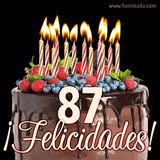 Animación de un pastel de chocolate decorado con frutas, velas encendidas y el número 87, acompañado de la palabra '¡Felicidades!' en elegante tipografía.
