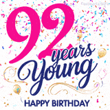 Colorful animated birthday GIF displaying the text '92 years Young' in bright pink and navy blue, with confetti falling and gold balloons floating.