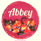 Beautifully decorated red velvet berry birthday cake with vibrant fruits and a glowing 'Abbey' name, adding a touch of sweetness and sparkle.