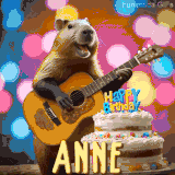 Animated birthday GIF showing a capybara playing guitar and singing beside a birthday cake with the name Anne in large letters and colorful bokeh lights in the background.