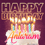 A colorful birthday cake topped with lit candles, with the words 'Happy Birthday Antaram' in bold glowing letters on a burgundy background. Animated flames add a festive touch.