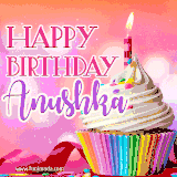 A vibrant birthday GIF featuring a rainbow-colored cupcake topped with white frosting, sprinkles, and a lit candle. The text reads 'Happy Birthday Anushka' in bold pink and violet letters with white outline.