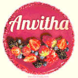 Beautifully decorated red velvet berry birthday cake with vibrant fruits and a glowing 'Anvitha' name, adding a touch of sweetness and sparkle.