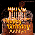 A rich chocolate cake topped with glowing birthday candles and surrounded by bright fireworks. The animated GIF displays the message 'Happy Birthday Ashtyn' in golden text.