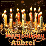 A glowing personalized birthday GIF with name Aubrei featuring lit candles with intricate designs, warm lighting, and the text 'Happy Birthday' in an elegant font.