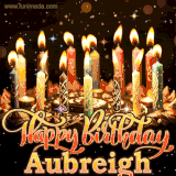 A glowing personalized birthday GIF with name Aubreigh featuring lit candles with intricate designs, warm lighting, and the text 'Happy Birthday' in an elegant font.