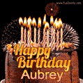 A rich chocolate cake topped with glowing birthday candles and surrounded by bright fireworks. The animated GIF displays the message 'Happy Birthday Aubrey' in golden text.