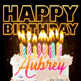A vibrant animated GIF featuring a delicious birthday cake topped with glowing candles and the name 'Aubrey' in elegant script, and the words 'Happy Birthday' on the black background.