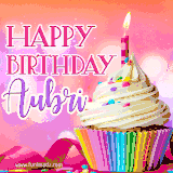 A vibrant birthday GIF featuring a rainbow-colored cupcake topped with white frosting, sprinkles, and a lit candle. The text reads 'Happy Birthday Aubri' in bold pink and violet letters with white outline.