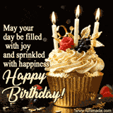 A cupcake in a golden cup, berries and three candles on top, text on the image says may your day be filled with joy and sprinkled with happiness.