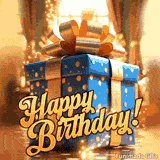 A 'Happy Birthday' GIF featuring a beautifully wrapped blue present with a shiny gold ribbon. Magical sparkles float around the gift box in a warm, festive room.
