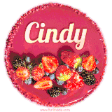 Beautifully decorated red velvet berry birthday cake with vibrant fruits and a glowing 'Cindy' name, adding a touch of sweetness and sparkle.