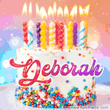 A cheerful white birthday cake with multicolor sprinkles, lit candles, and 'Deborah' written in vibrant letters, in an animated GIF.