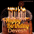 A rich chocolate cake topped with glowing birthday candles and surrounded by bright fireworks. The animated GIF displays the message 'Happy Birthday Devesh' in golden text.