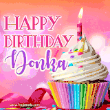 A vibrant birthday GIF featuring a rainbow-colored cupcake topped with white frosting, sprinkles, and a lit candle. The text reads 'Happy Birthday Donka' in bold pink and violet letters with white outline.