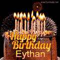A rich chocolate cake topped with glowing birthday candles and surrounded by bright fireworks. The animated GIF displays the message 'Happy Birthday Eythan' in golden text.