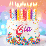 A cheerful white birthday cake with multicolor sprinkles, lit candles, and 'Gia' written in vibrant letters, in an animated GIF.