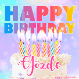 A vibrant animated name GIF with the words 'Happy Birthday Gözde' with colorful candles on a creamy cake. The background sparkles with pastel shades, adding a festive touch.