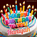 A colorful birthday cake topped with lit candles, with the words 'Happy Birthday Haniyah' in bold glowing letters on a burgundy background. Animated flames add a festive touch.