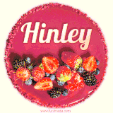 Beautifully decorated red velvet berry birthday cake with vibrant fruits and a glowing 'Hinley' name, adding a touch of sweetness and sparkle.