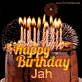 A rich chocolate cake topped with glowing birthday candles and surrounded by bright fireworks. The animated GIF displays the message 'Happy Birthday Jah' in golden text.