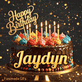 Yellow script spelling the name Jaydyn on a classic chocolate cake with a dark glaze under warm candlelight.