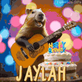 Animated birthday GIF showing a capybara playing guitar and singing beside a birthday cake with the name Jaylah in large letters and colorful bokeh lights in the background.