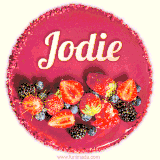 Beautifully decorated red velvet berry birthday cake with vibrant fruits and a glowing 'Jodie' name, adding a touch of sweetness and sparkle.