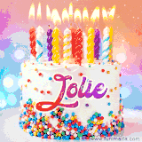 A cheerful white birthday cake with multicolor sprinkles, lit candles, and 'Jolie' written in vibrant letters, in an animated GIF.