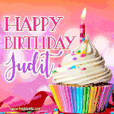 A vibrant birthday GIF featuring a rainbow-colored cupcake topped with white frosting, sprinkles, and a lit candle. The text reads 'Happy Birthday Judit' in bold pink and violet letters with white outline.