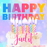 A vibrant animated name GIF with the words 'Happy Birthday Judit' with colorful candles on a creamy cake. The background sparkles with pastel shades, adding a festive touch.