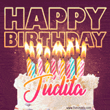 A colorful birthday cake topped with lit candles, with the words 'Happy Birthday Judita' in bold glowing letters on a burgundy background. Animated flames add a festive touch.