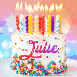 A cheerful white birthday cake with multicolor sprinkles, lit candles, and 'Julie' written in vibrant letters, in an animated GIF.