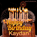 A rich chocolate cake topped with glowing birthday candles and surrounded by bright fireworks. The animated GIF displays the message 'Happy Birthday Kaydan' in golden text.