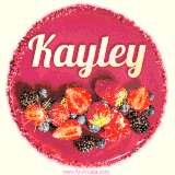 Beautifully decorated red velvet berry birthday cake with vibrant fruits and a glowing 'Kayley' name, adding a touch of sweetness and sparkle.
