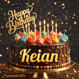 Yellow script spelling the name Keian on a classic chocolate cake with a dark glaze under warm candlelight.